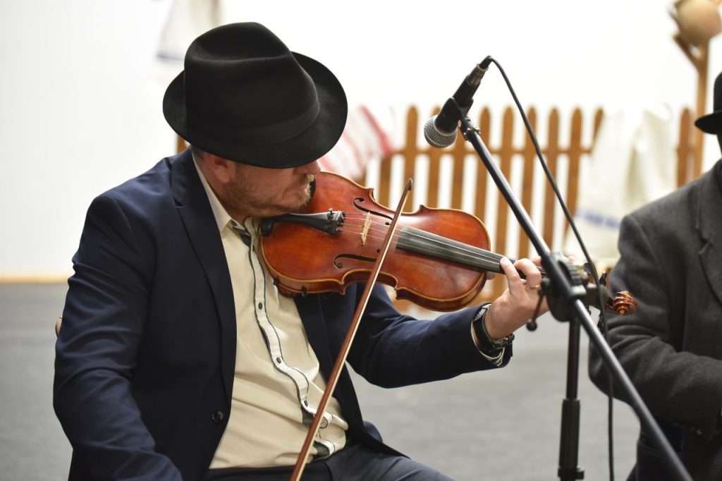 A musician in traditional attire plays the violin passionately during a performance.